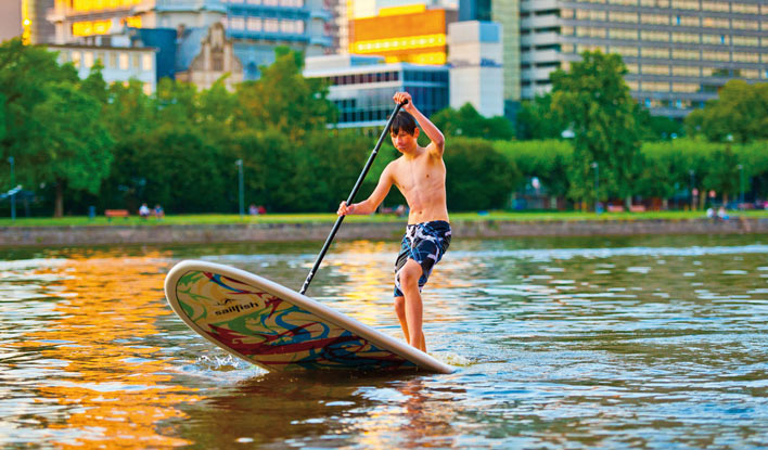 junger-fkv-paddler-SUP-stehend-in-frankfurt-am-main Ein SUP-Paddler des Frankfurter Kanu-Vereins vor der Frankfurter Skyline